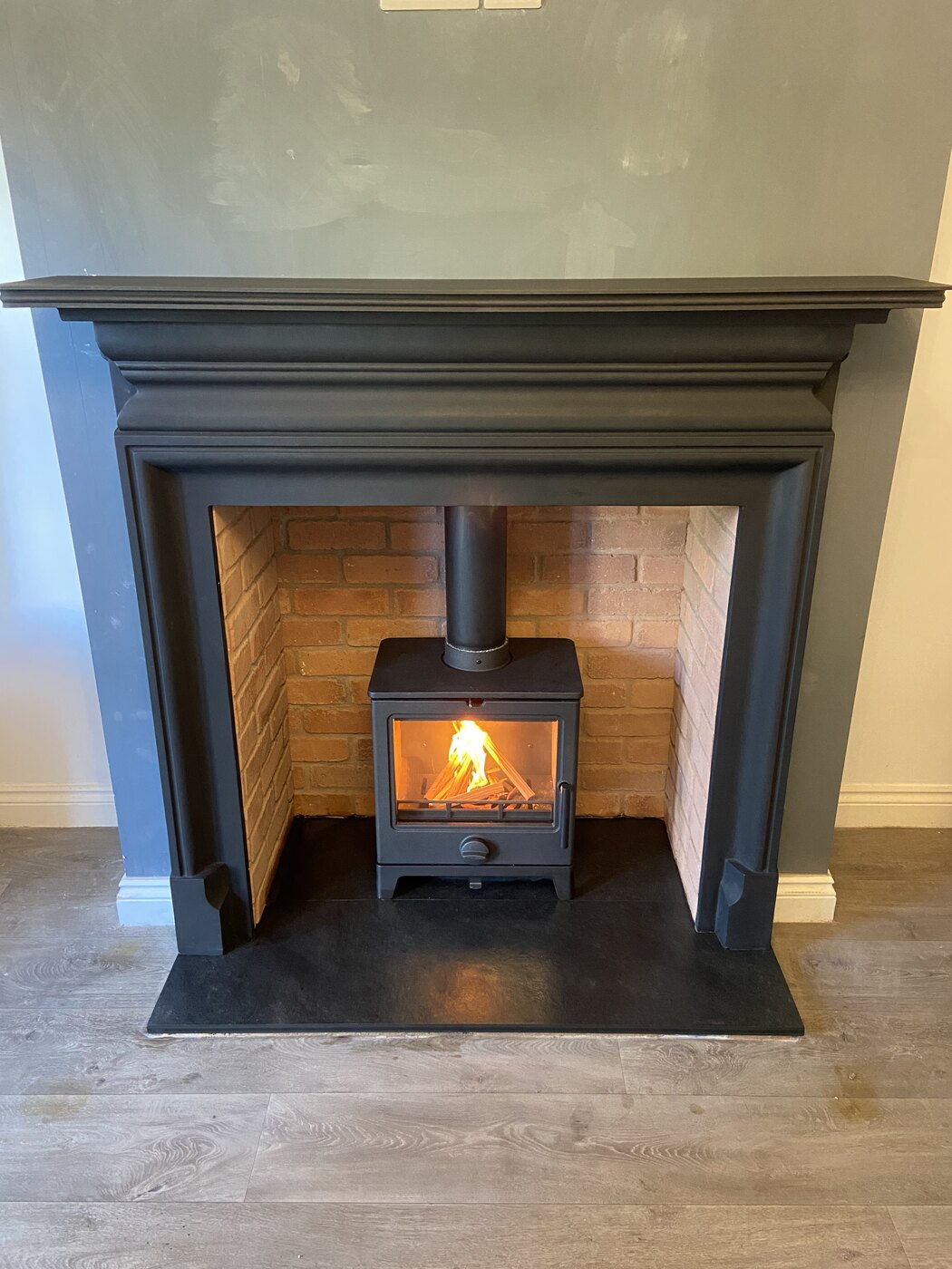 Lit log burner installed in a dark timber fireplace